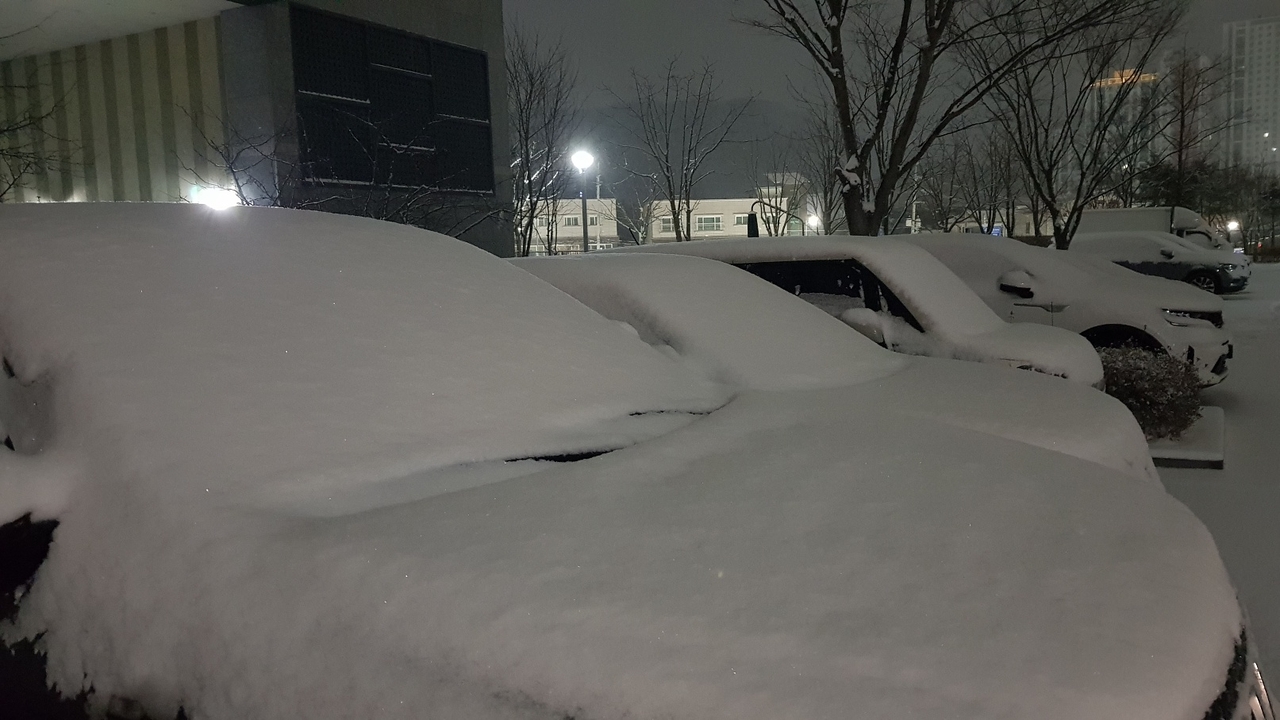 Cars in a parking lot in the central city of Daejeon are covered by snow on Tuesday. (Yonhap)