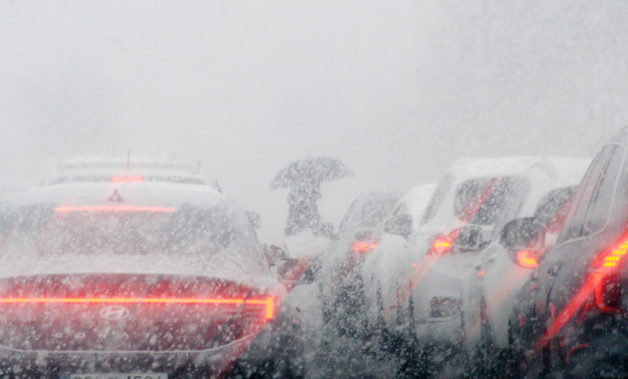 Vehicles struggle through thick snowfall in Jeonju on Tuesday, as heavy now warnings grip the region. (Yonhap)