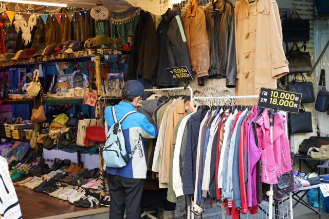 A customer checks clothes at one of the vintage shop in Dongmyo Flea Market in Jongno-gu, central Seoul. (Lee Si-jin/The Korea Herald