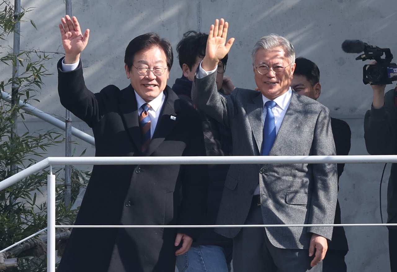 Main opposition Democratic Party of Korea Chair Rep. Lee Jae-myung (front, left) waves during a meeting with former liberal President Moon Jae-in at Moon's residence in Yangsan, South Gyeongsang Province on Thursday. (Yonhap)