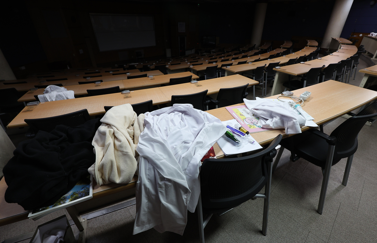 교육부가 ‘의대 증원 정책’에 반대하며 동맹 휴학에 돌입한 의과대학 학생들의 복귀 방안을 2월 안으로 발표하겠다고 밝혔다. 사진은 한 의과대학 강의실에 남겨진 의사 가운. [연합]