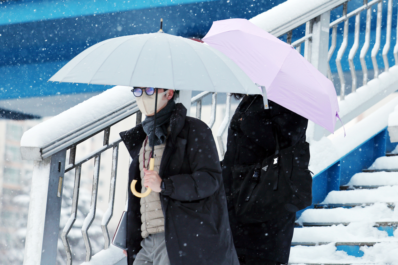 People are walking with umbrellas on a pedestrian bridge over Mujin-daero in Seo-gu, Gwangju, on Tuesday. (Yonhap)