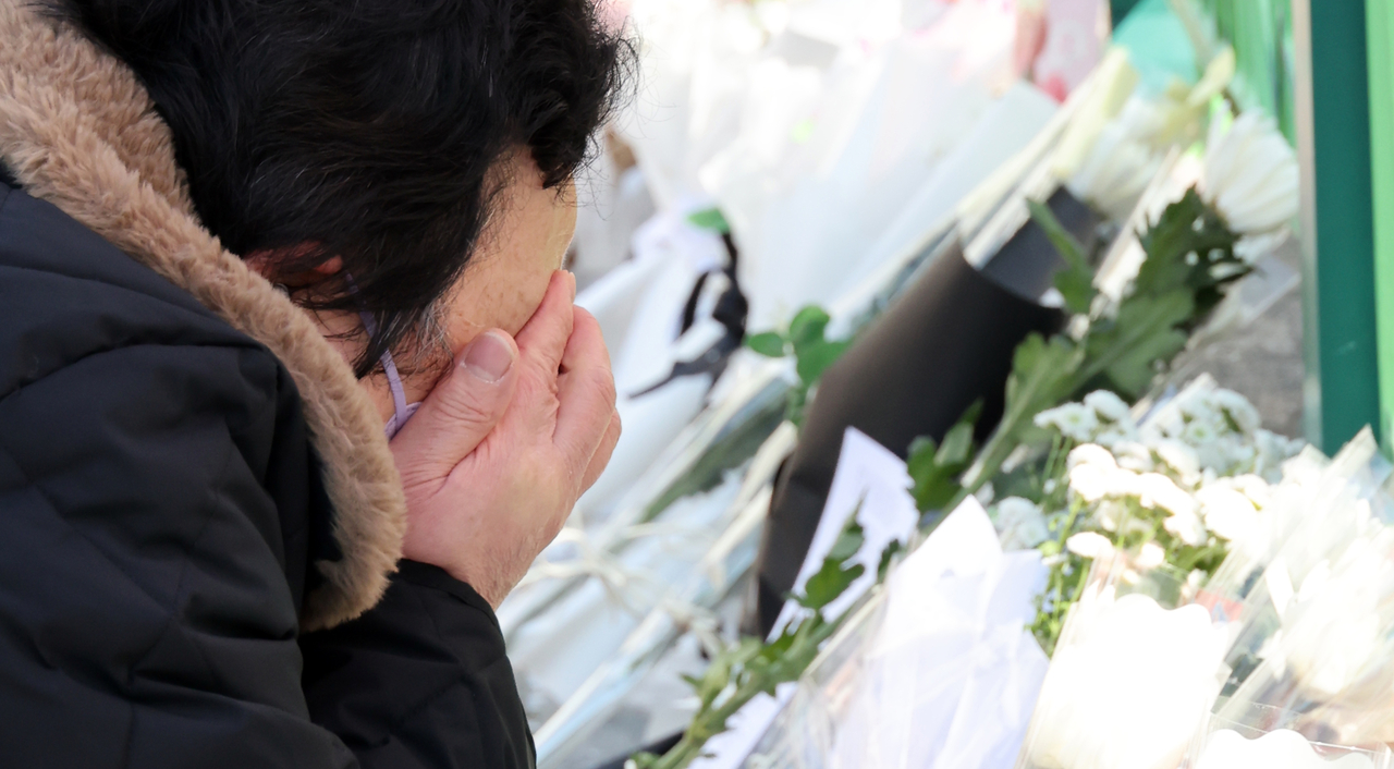 지난 11일 오후 초등학생 피살사건이 발생한 대전 서구 관저동의 한 초등학교 정문 옆 담장에서 한 시민이 눈물을 흘리며 고 김하늘(8) 양을 추모하고 있다. [뉴시스]