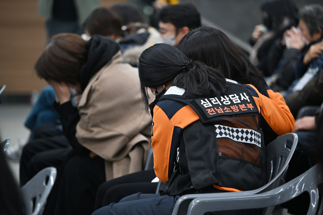 A psychological counselor comforts a bereaved family member as she sheds tears at a joint memorial service for the 49th anniversary of the Jeju Air passenger plane disaster at the Muan International Airport in Muan, South Jeolla Province, on the morning of Feb. 15, the 49th day of the tragedy. (Yonhap)