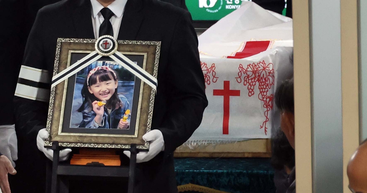 A family member of Kim Ha-neul, an 8-year-old stabbing victim, carries her portrait during her funeral service in the central city of Daejeon on Friday. (Yonhap)
