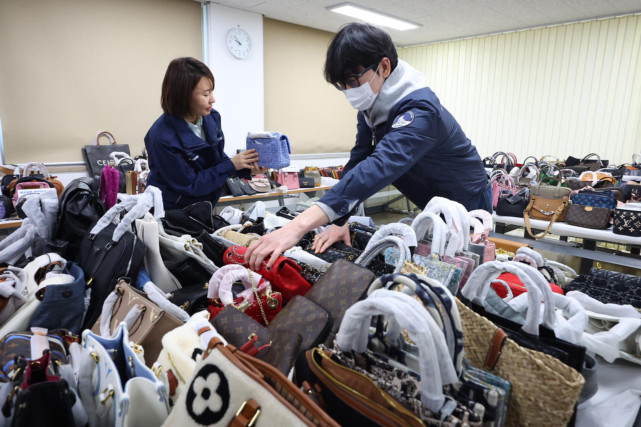 Officials check stacks of counterfeit bags seized from the Myeongdong shop. (Yonhap)