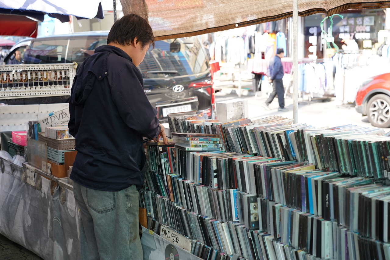 A person looks through CDs and vinyl on display at a record shop in Hwanghak-dong Flea Market. (Lee Si-jin/The Korea Herald)