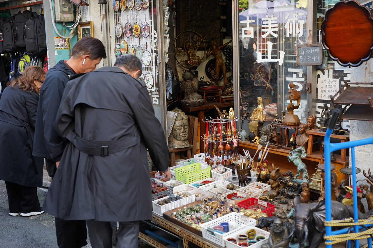 Visitors check out antiques and crafts at one of Hwanghakdong Flea Market's shops. (Lee Si-jin/The Korea Herald)