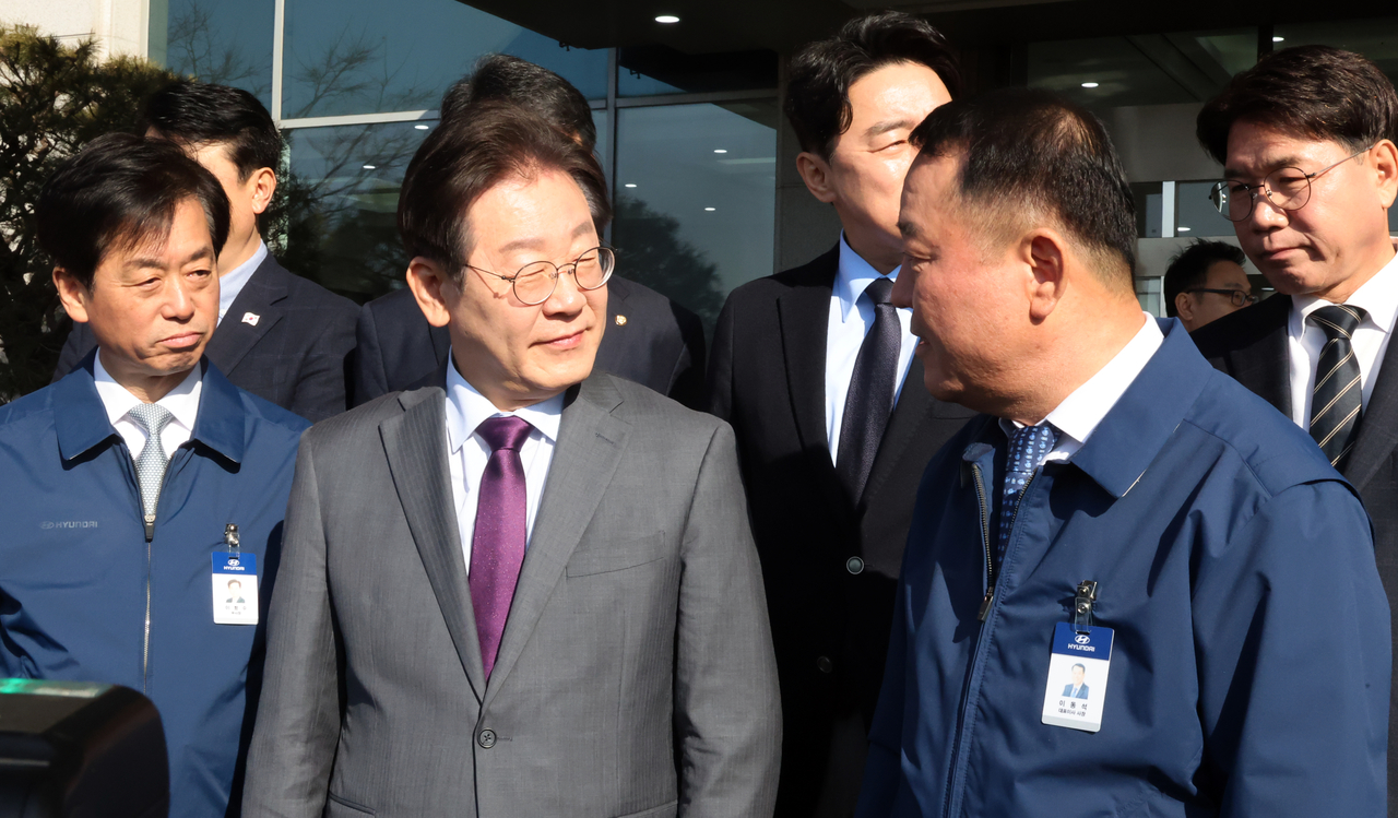Main opposition leader Lee Jae-myung, center left, talks with Hyundai Motor President and Chief Executive Officer Lee Dong-seock during a visit to the Hyundai Motor manufacturing plant in Asan, South Chungcheong Province on Thursday. Yonhap
