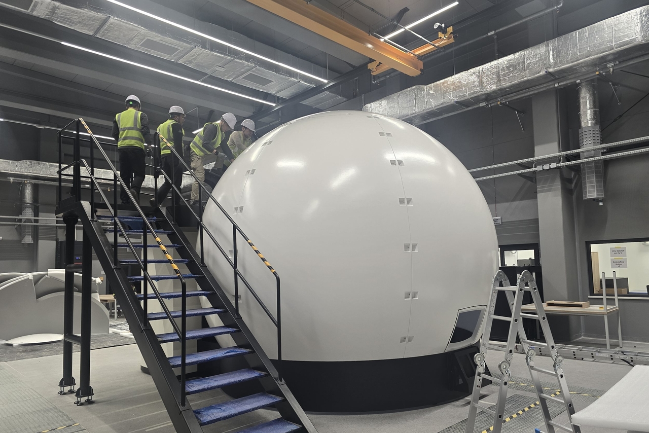 Workers inspect a fighter jet simulator transported to Poland. (CJ Logistics)