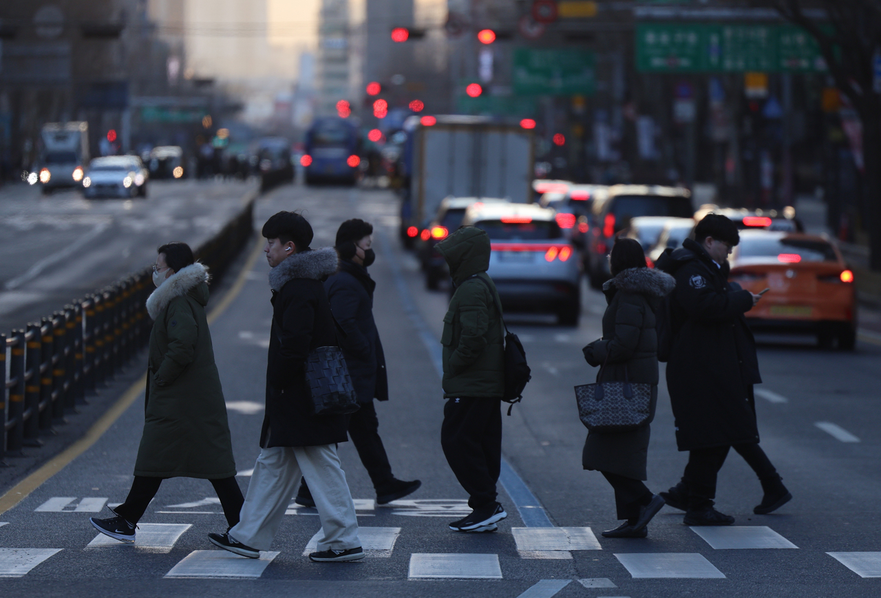 Passersby cross a road in central Seoul on Feb. 7. (Newsis)