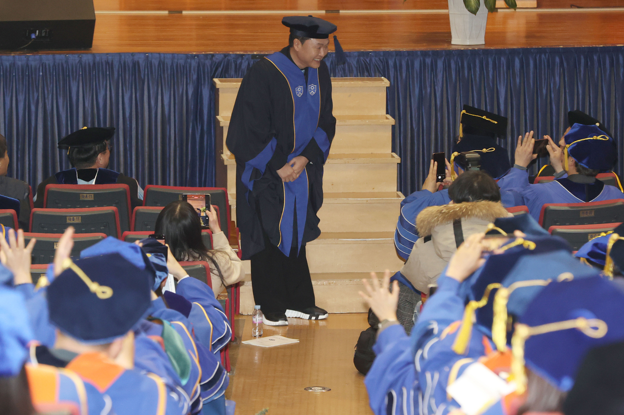 Psy greets the crowd with a bow as graduates welcome him with applause ahead of his honorary degree conferral at Yonsei University in Seoul on Monday. (Yonhap)