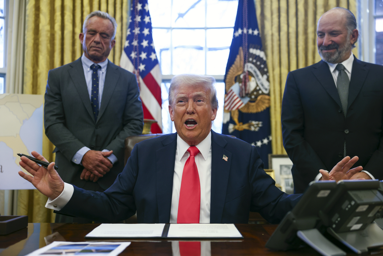 US President Donald Trump speaks to the press after signing an executive order, alongside Secretary of Health and Human Services Robert Kennedy Jr. (left) and Secretary of Commerce Howard Lutnick (right), at the Oval Office of the White House in Washington on Tuesday. (AFP-Yonhap)