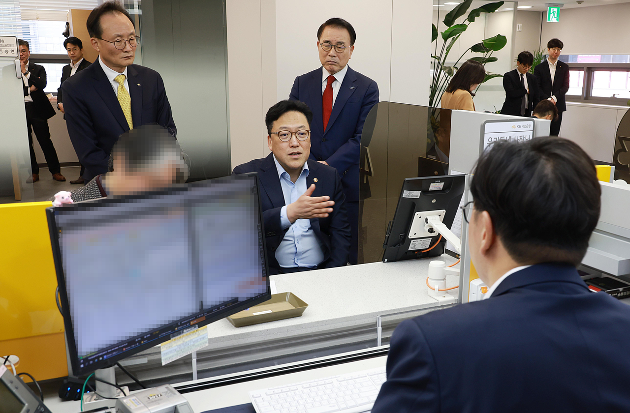김병환(가운데) 금융위원장이 27일 서울 중구 KB국민은행 충무로역 종합금융센터에 마련된 소상공인 금융지원 사전상담 현장에서 운영현황을 점검하고 있다. 왼쪽부터 이환주 KB국민은행장, 김 위원장, 조용병 은행연합회장. [금융위 제공]