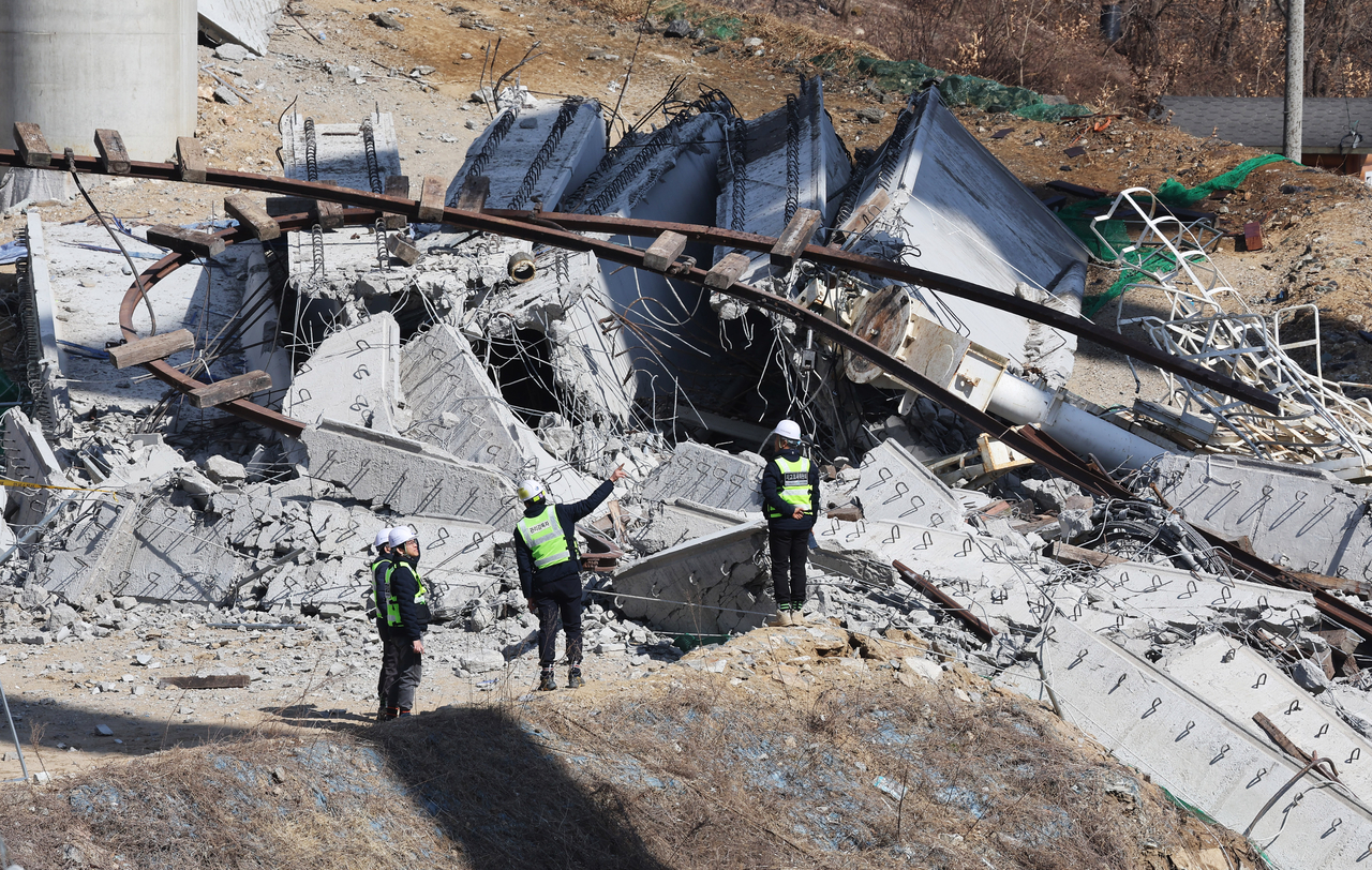 Officials investigate the site where a bridge under construction collapsed, killing four and injuring six, along a Seoul-Sejong highway, in Anseong, Gyeonggi Province, Feb. 25. (Yonhap)