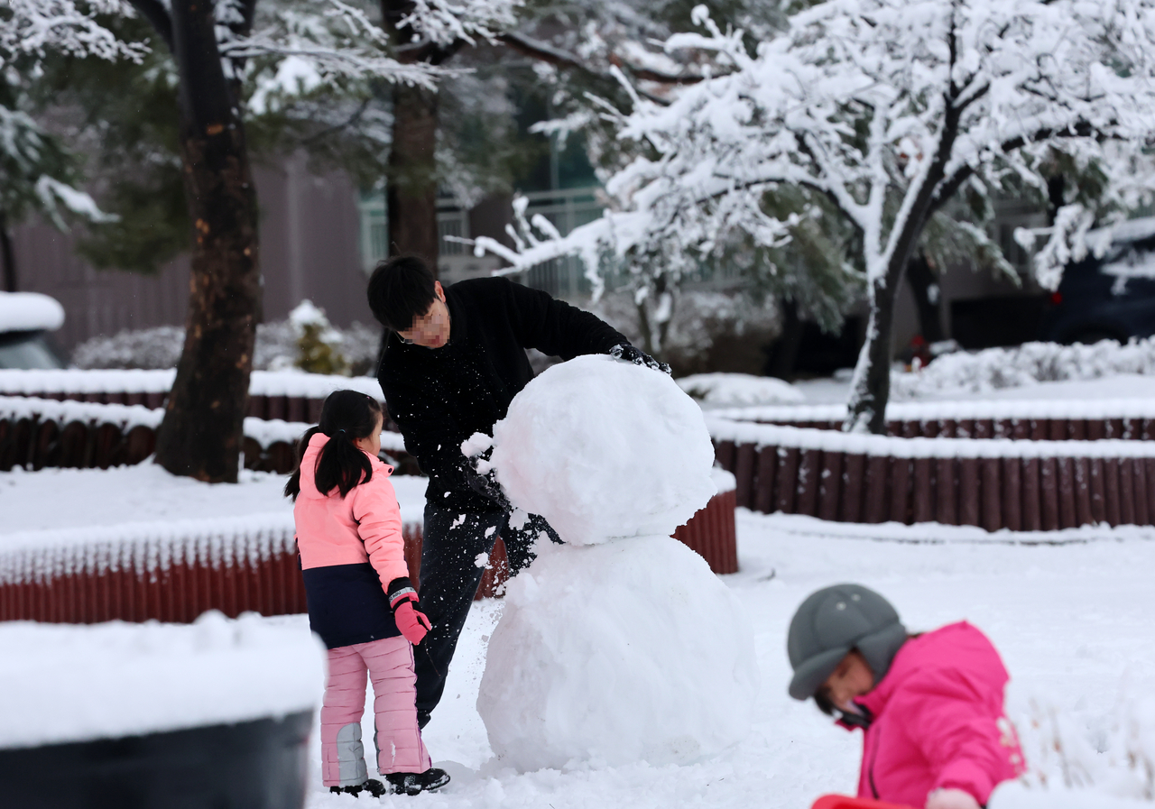 A family makes a snowman together in a residential neighborhood in Gangneung, Gangwon Province, Monday. (Yonhap)