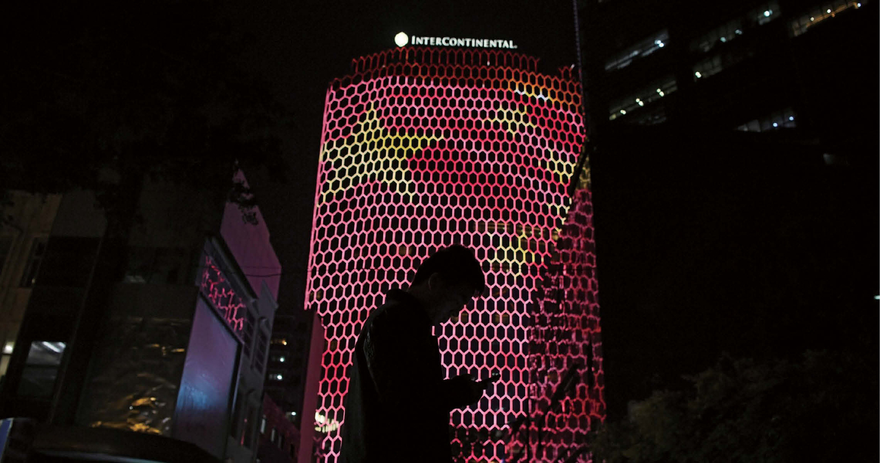 A man looks at his phone near a giant image of the Chinese national flag on the side of a building in Beijing, during the ongoing 19th Communist Party Congress on October 23, 2017. [AFP]