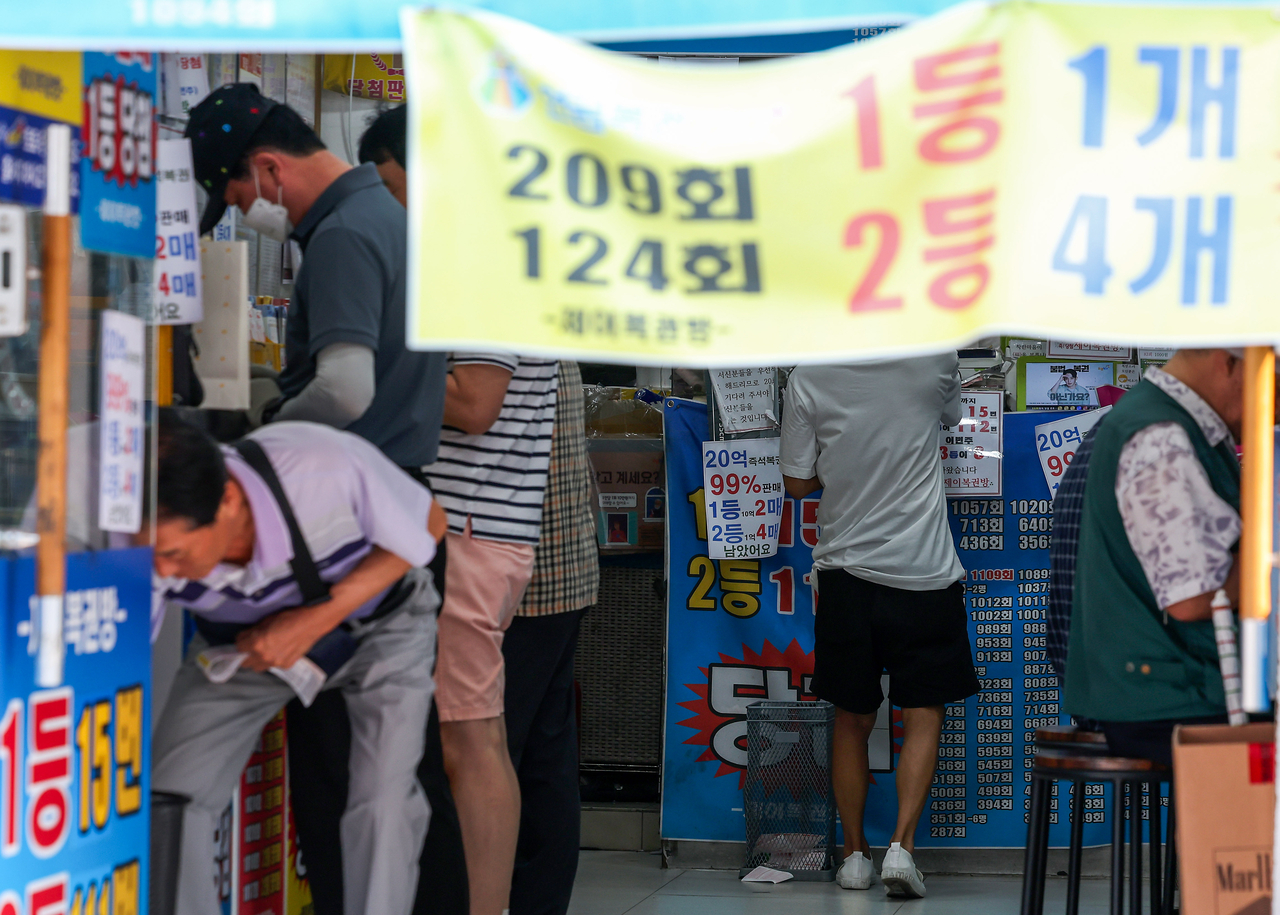 Customers purchase lottery tickets at a downtown Seoul retailer in July 2024. (Newsis)