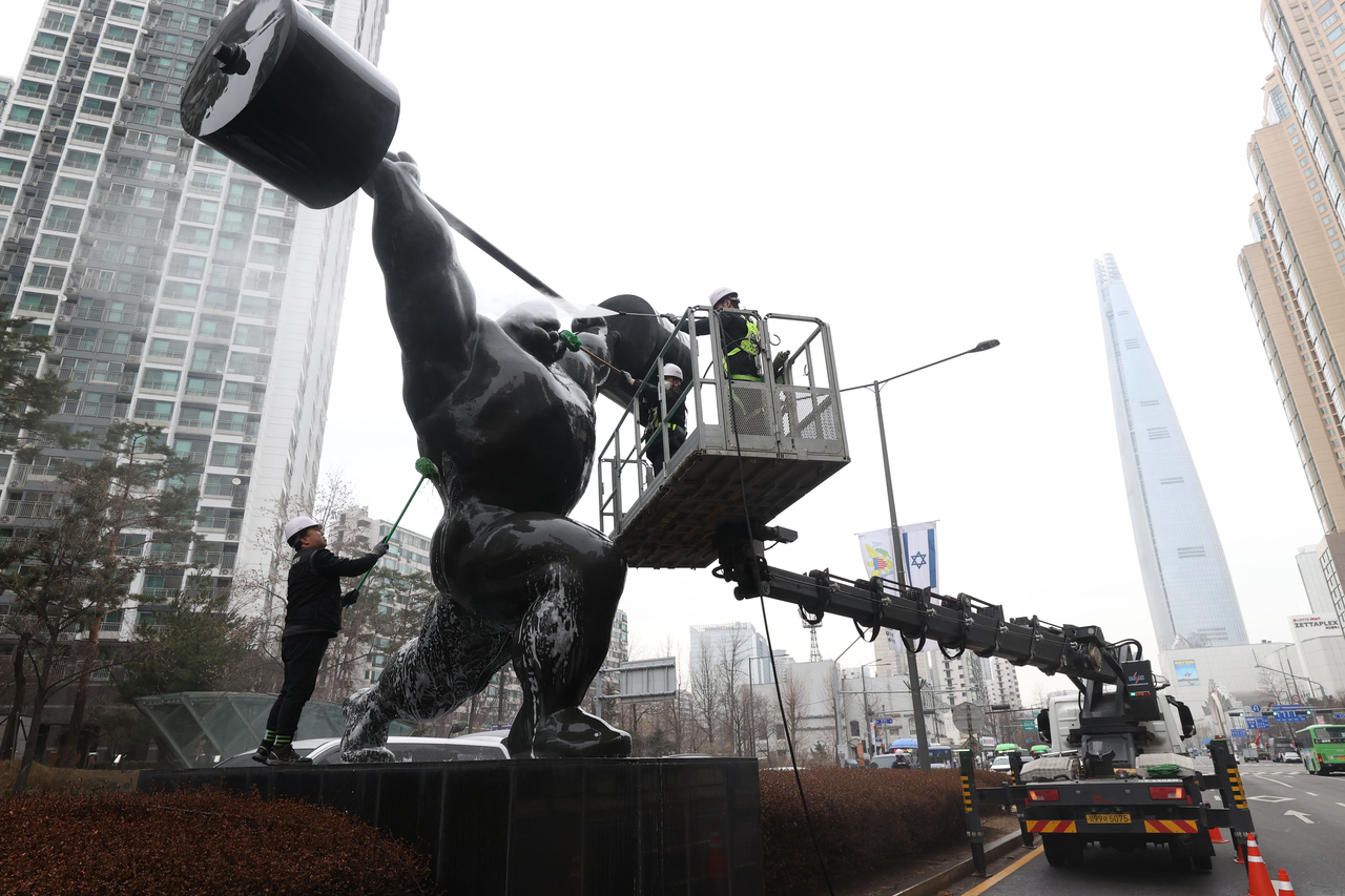 Workers are seen using brushes and a high-pressure washer on Wednesday to clean dust pollution off a statue commemorating the 1988 Seoul Olympics near Jamsil Sports Complex in Seoul. (Yonhap)