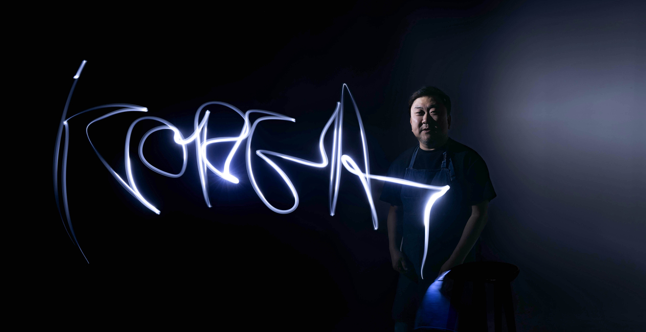 Calligraphy artist Lee Sang-hyun writes "KOREA" with a glowing pen before an interview at Herald Square in Yongsan-gu, Seoul, on Feb. 17. (Im Se-jun/The Korea Herald)