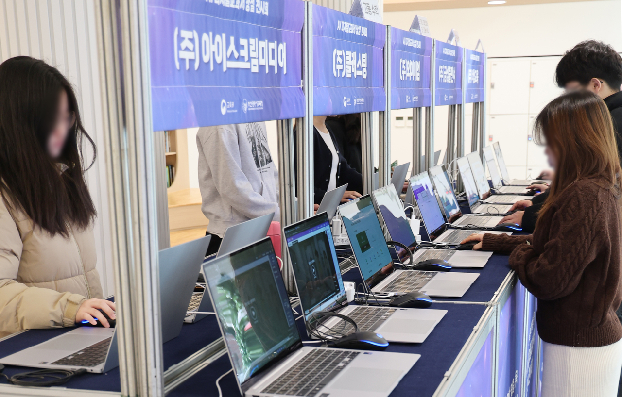 Teachers and students examine AI-based digital textbooks at an exhibition in Busan on Feb. 21. (Yonhap)