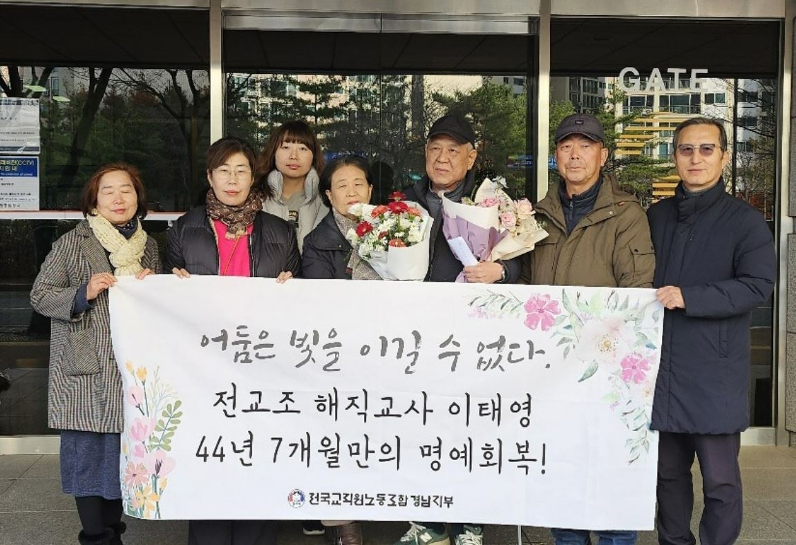 Lee Tae-yeong (third from right) poses with his wife (fourth from right) on Dec. 11 in front of the Busan District Court, after being exonerated of accusations made against him in 1980. (Photo courtesy of the Korean Teachers & Educational Worker's Union)
