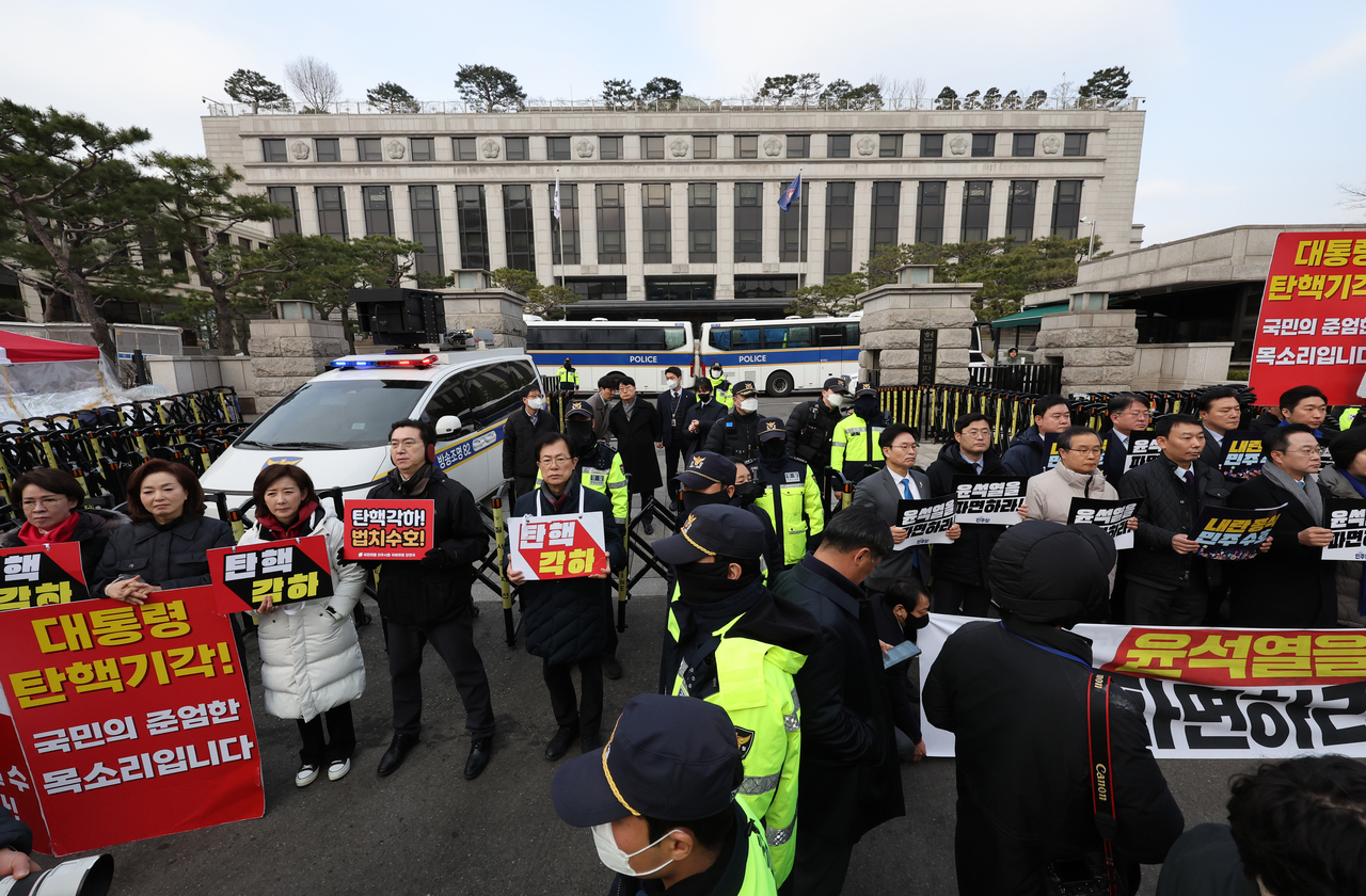 Lawmakers from the ruling People Power Party (left) and the main opposition Democratic Party (right) protest in front of the Constitutional Court of Korea in Jongno-gu, Seoul, Thursday. (Yonhap)