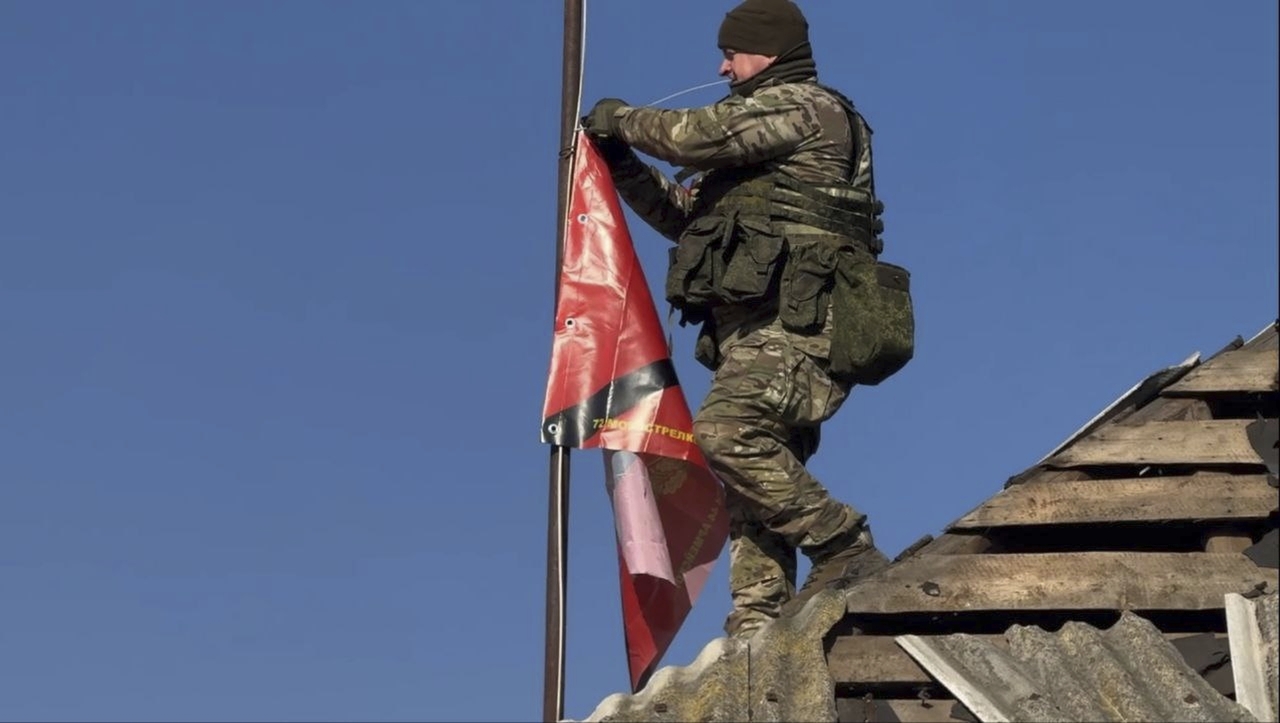 In this photo distributed by the Russian Defense Ministry Press Service on Monday, March 17, 2025, a Russian soldier prepares to raise a flag atop a house in Staraya Sorochina, a village in the Sudzha district of the Kursk region of Russia after it was taken over by Russian troops. (Yonhap - Russian Defense Ministry Press Service via AP)