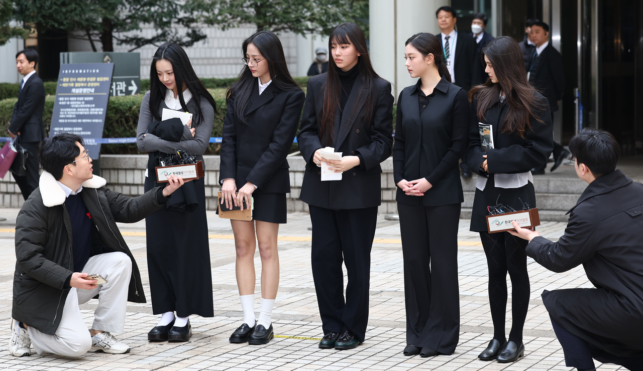 NewJeans members respond to reporters' questions as they leave the Seoul Central District Court, March 7. (Yonhap)