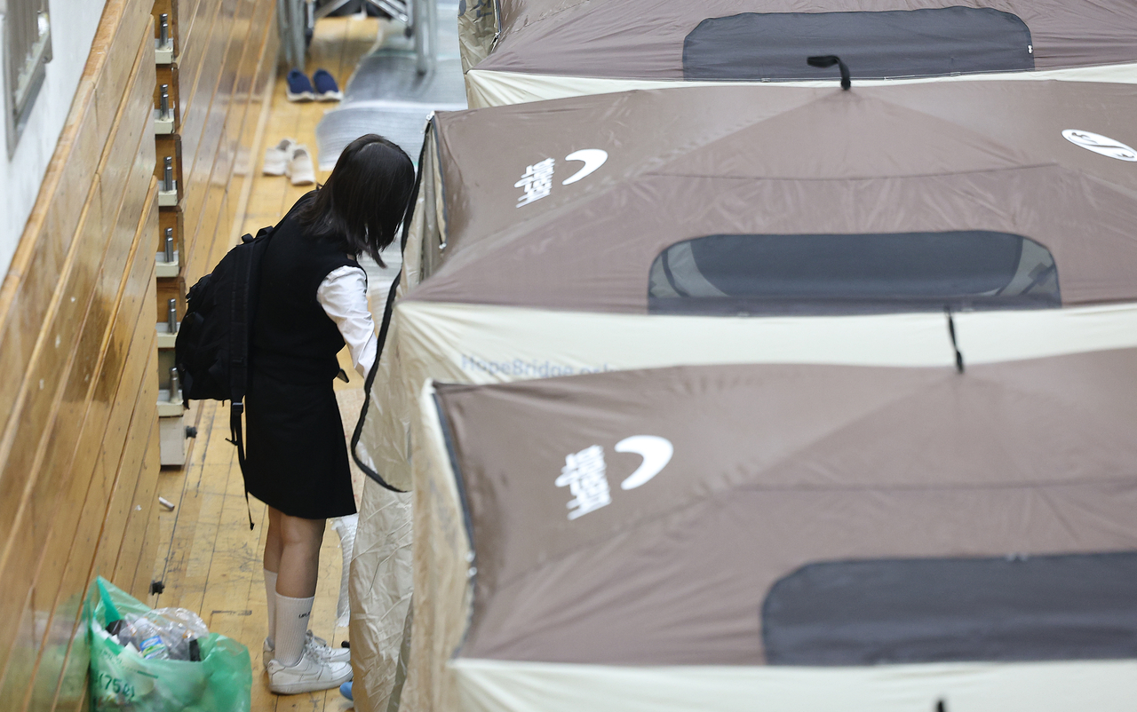 A student is seen leaving a tent at the evacuation shelter set up at Uiseong Gymnasium to head to school on Monday. (Yonhap)