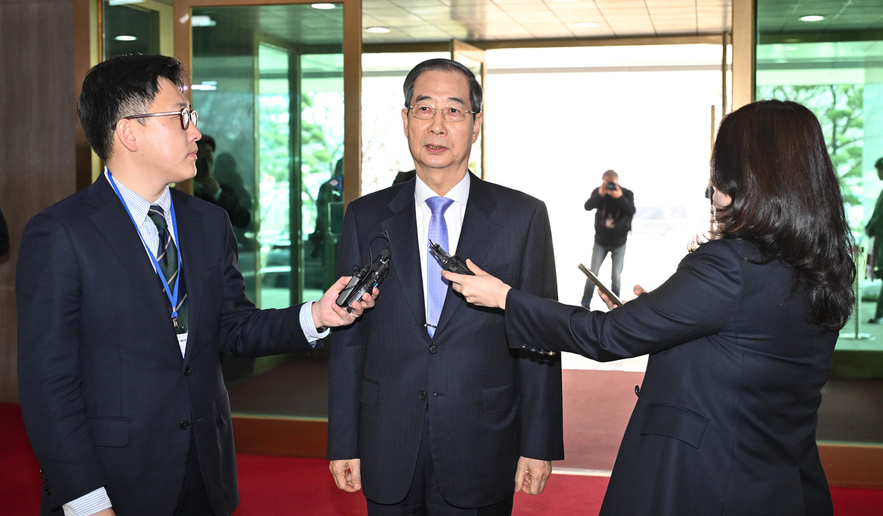 Acting President and Prime Minister Han Duck-soo talks to reporters after entering the Seoul Government Complex for the first time since his impeachment in December, on Monday. The Constitutional Court reinstated him as acting president earlier in the day. (Im Se-jun / The Korea Herald)