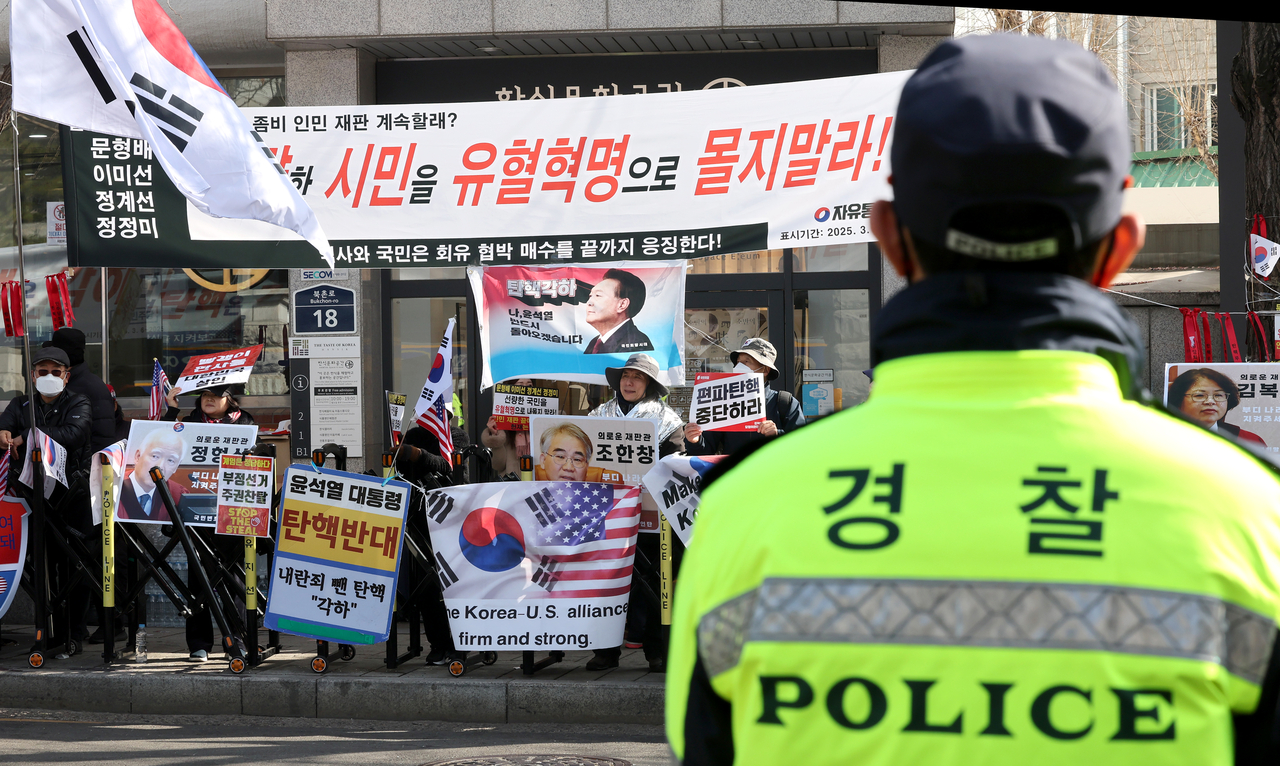 This photo shows a mobile police squad unit officer facing protesters in front of the Constitutional Court in Seoul, March 13. (Pool photo via Yonhap)