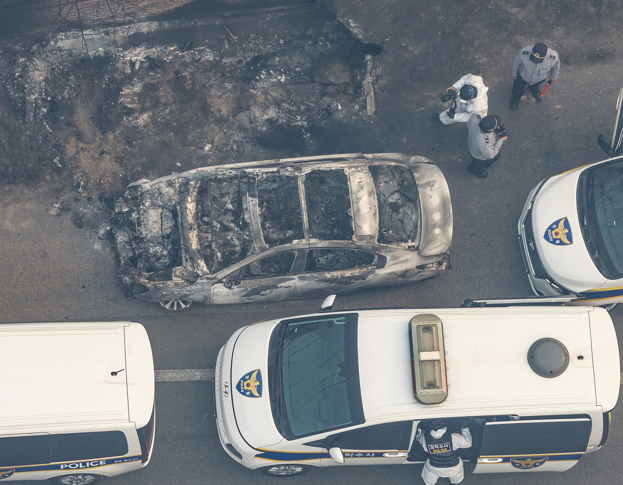 Police officials examine a car burned to ashes in Yeongdeok, North Gyeongsang Province, after a wildfire broke out Tuesday. Three people were found dead at the site. (Yonhap)