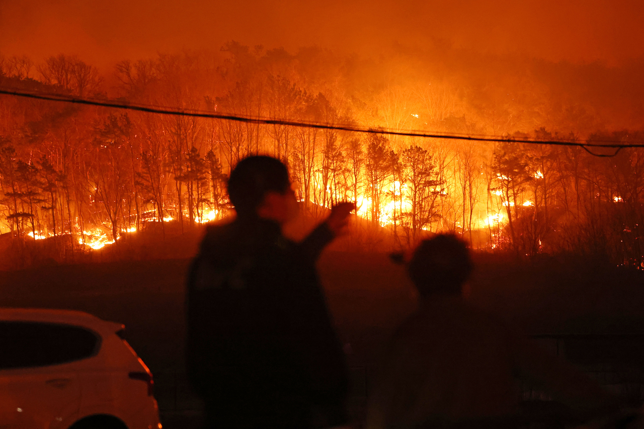 A resident watches a wildfire spreading to a nearby hill in Andong, North Gyeongsang Province, on Tuesday. (Yonhap)