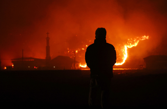 A resident watches wildfires burn Tuesday night in Andong, North Gyeongsang Province. (Yonhap)