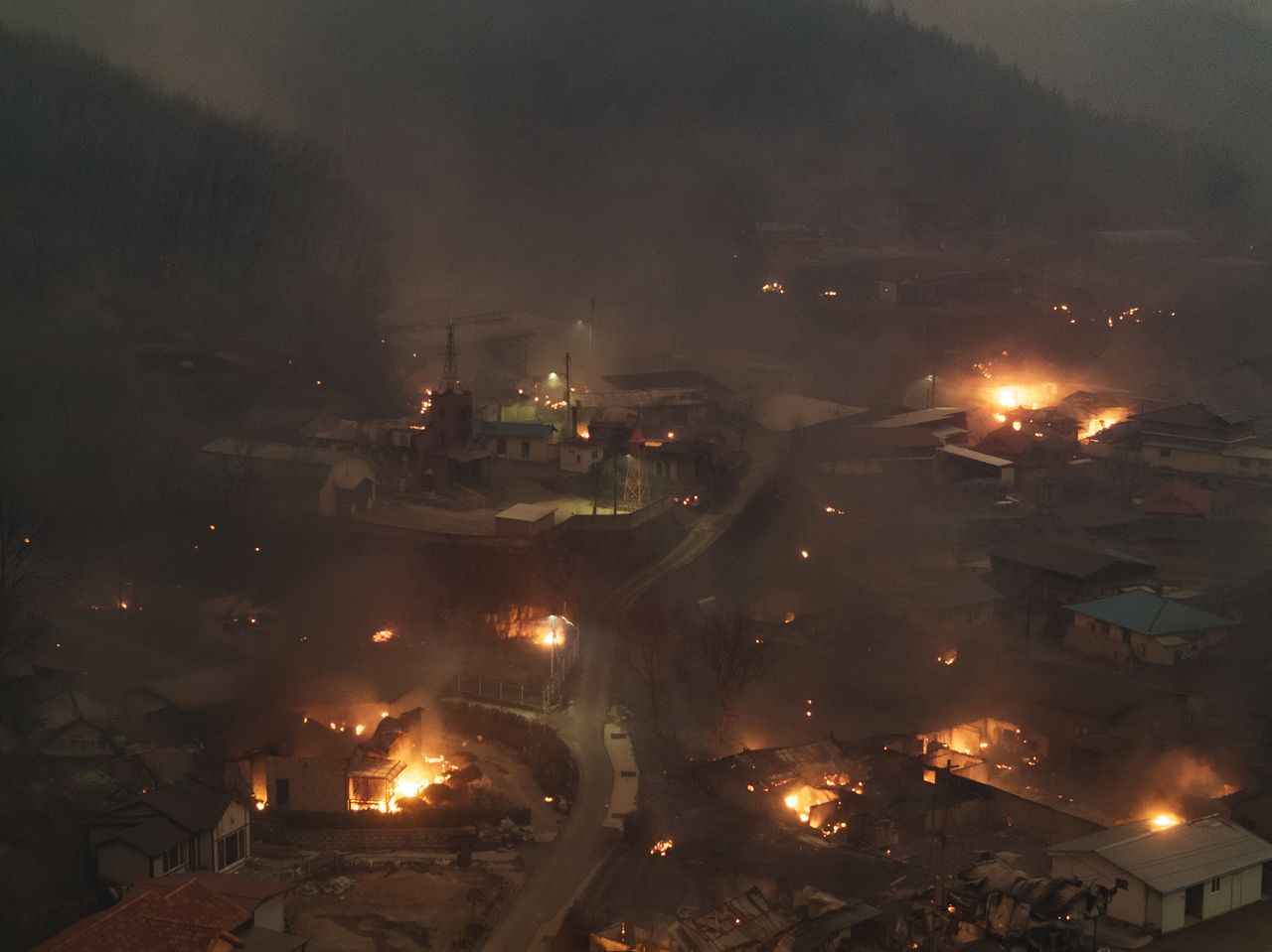 Parts of a village in Uiseong County, North Gyeongsang Province, are seen burning Tuesday night as embers carried by strong winds ignite new flames. (Yonhap)