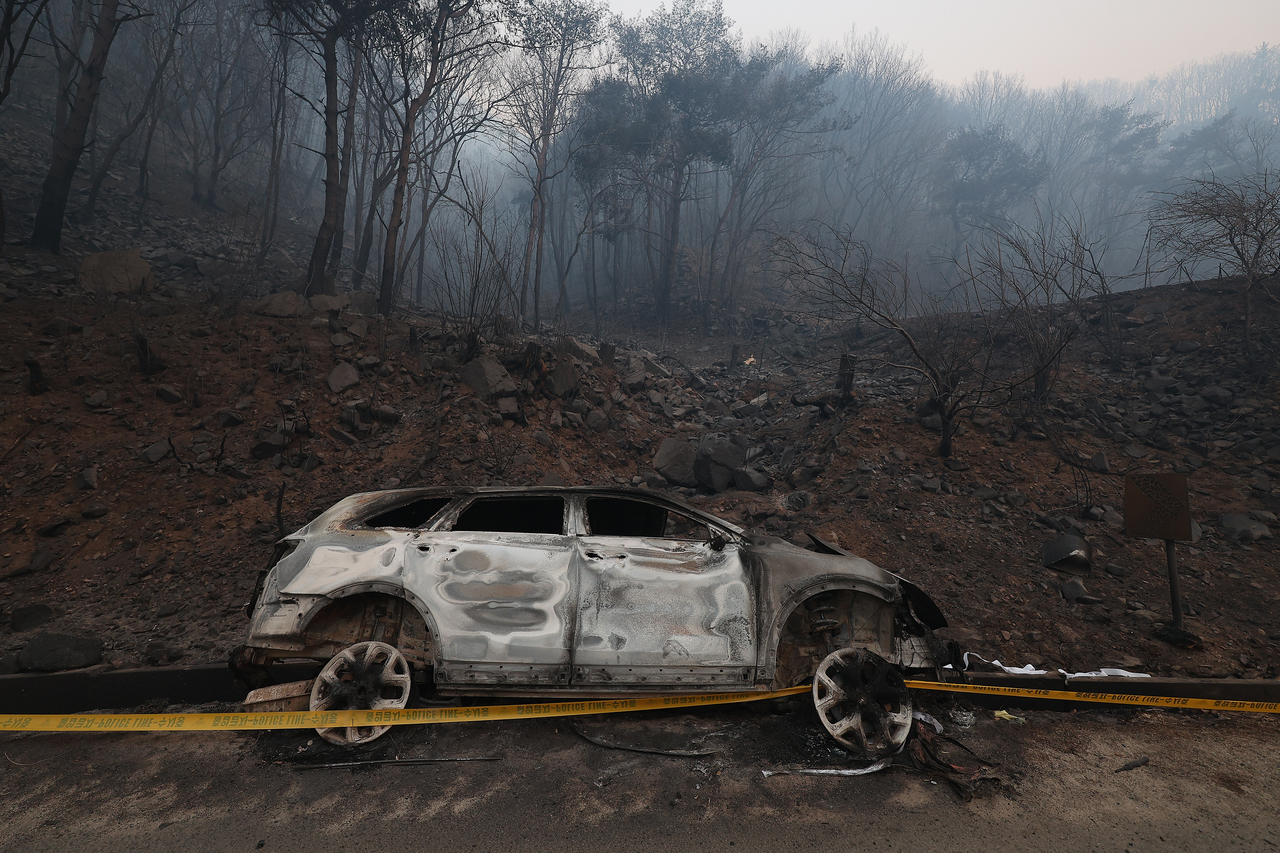 A vehicle destroyed by wildfires is seen abandoned on the side of a road in Youngyang, North Gyeongsang Province, on Wednesday. (Yonhap)