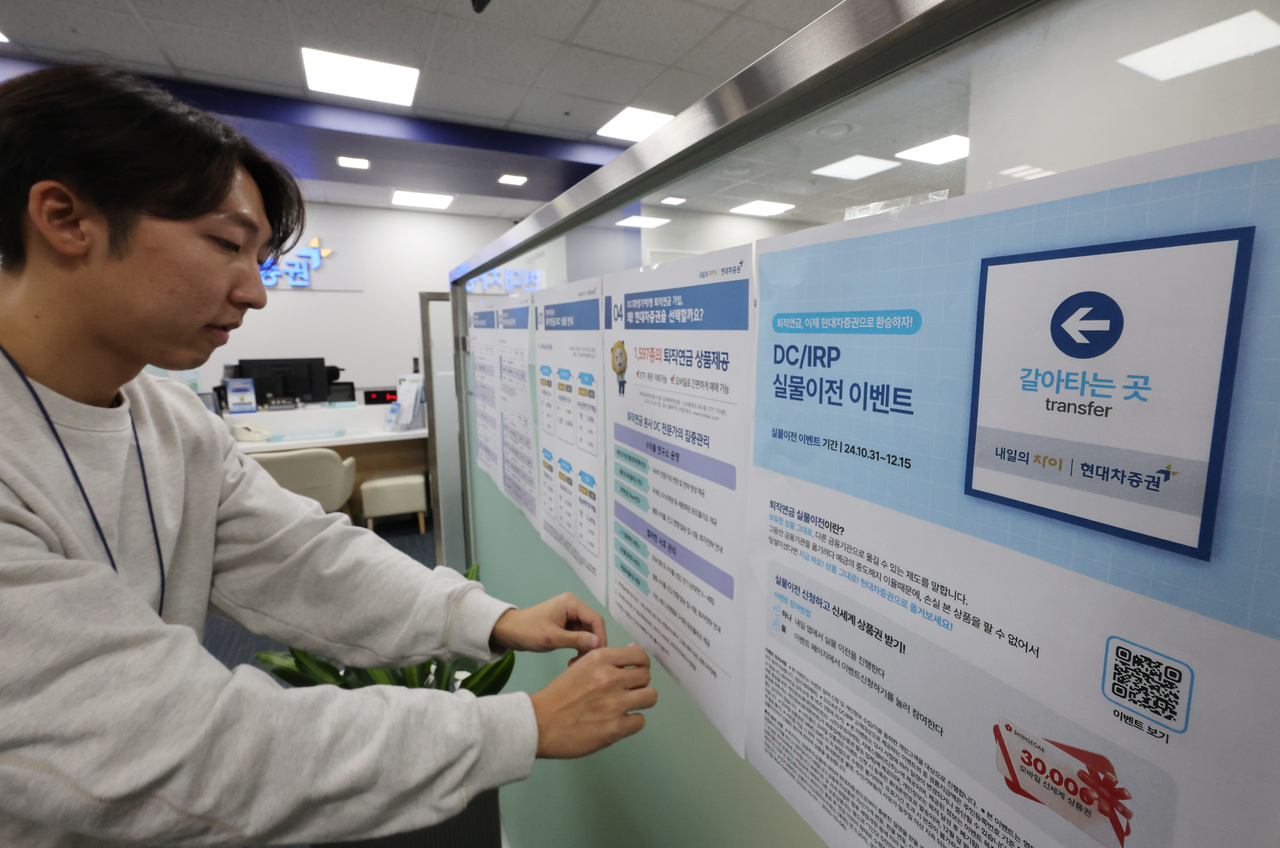 기존 퇴직연금 상품을 다른 금융사로 옮길 수 있는 ‘퇴직연금 실물이전 서비스’가 31일부터 시작된다. 약 400조원 규모의 퇴직연금 시장에서 ‘머니무브’를 기대하는 은행·증권업계 경쟁이 치열해질 것으로 예상된다. 사진은 31일 서울 한 증권사 영업점에서 관계자가 관련 홍보물을 부착하는 모습 [연합]