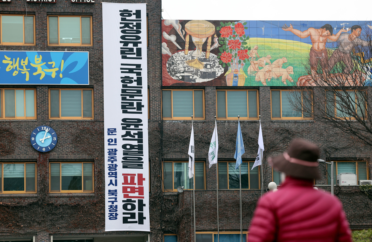 문인 광주 북구청장은 10일 청사에 ‘헌정유린 국헌문란 윤석열을 파면하라’는 현수막을 걸었다. 한 시민이 청사에 걸린 현수막을 보고 있는 모습. 2025.3.10 [독자 제공. 재판매 및 DB 금지] <연합뉴스>