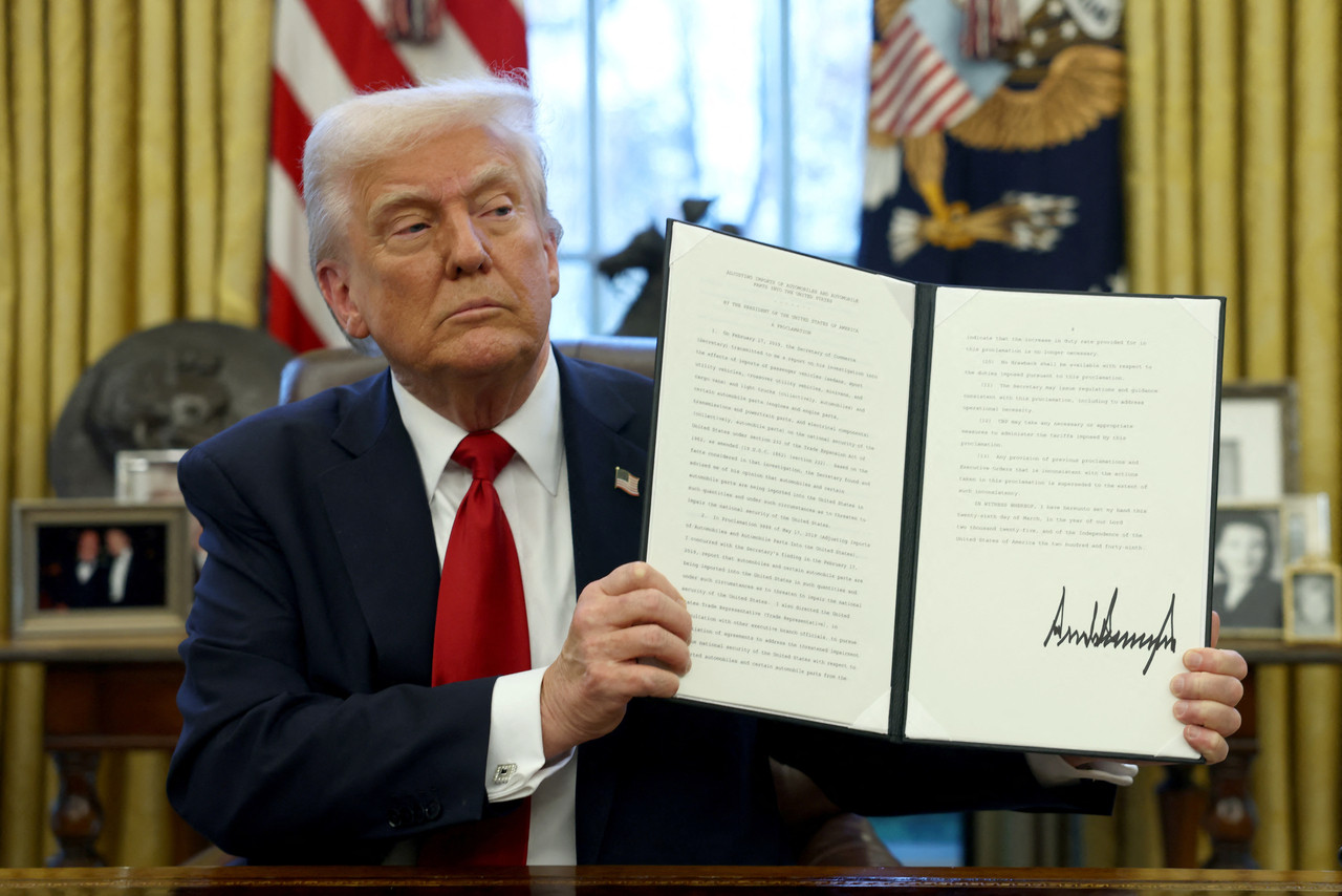 US President Donald Trump shows a signed document in the Oval Office at the White House in Washington on Wednesday. (Reuters-Yonhap)