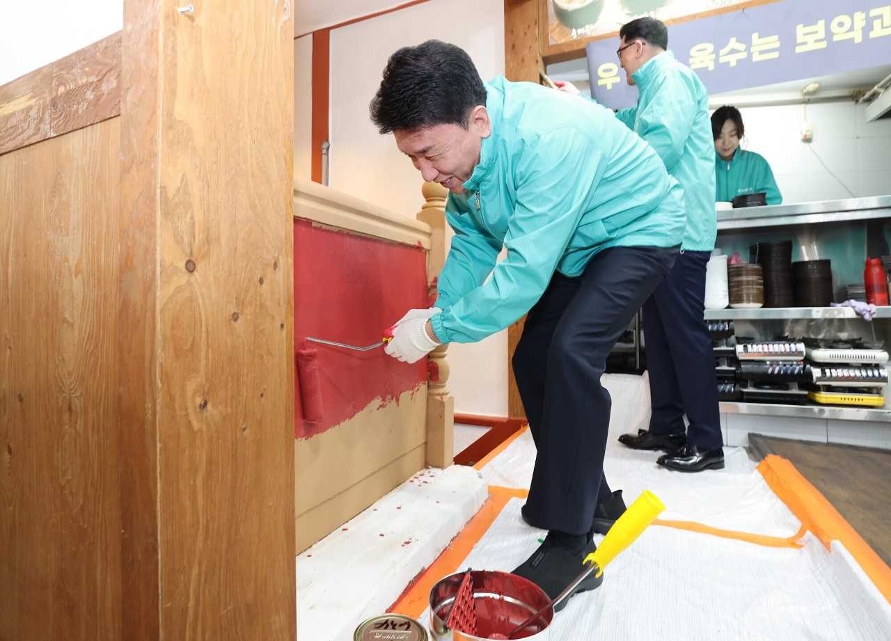 Hana Financial Group CEO Ham Young-joo works on repairing a business place owned by a small merchant, Wednesday. (Hana Financial Group)