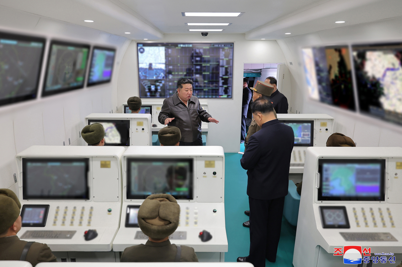 This image, published on Thursday, shows North Korean leader Kim Jong-un speaking to officials aboard an airplane similar to the South Korean Air Force's airborne early warning and control aircraft. (KCNA)
