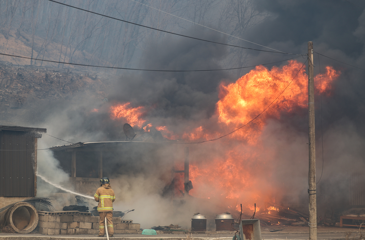 A firefighter extinguishes flames at a residential area in Uiseong-gun, North Gyeongsang Province on Tuesday. (Yonhap)