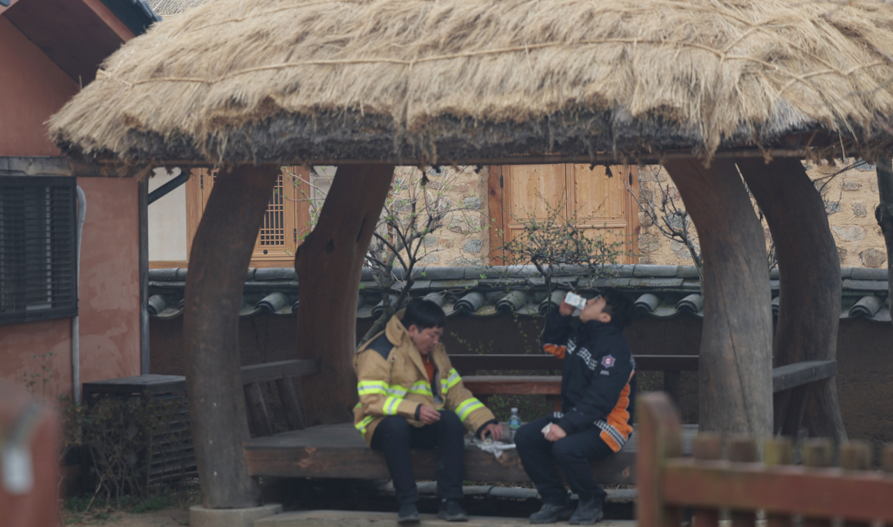 On Thursday morning, after the blaze receded, two firefighters eat a quick lunch of gimbap in Hahoe Village, Andong, North Gyeongsang Province. (Yonhap)