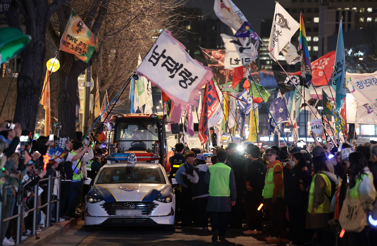 26일 서울 종로구 경복궁역 인근 자하문로에서 윤석열 대통령 탄핵을 촉구하는 단체와 시민들이 전국농민회총연맹(전농)의 트랙터를 막고 있는 경찰차 이동을 요구하며 구호를 외치고 있다. [연합]