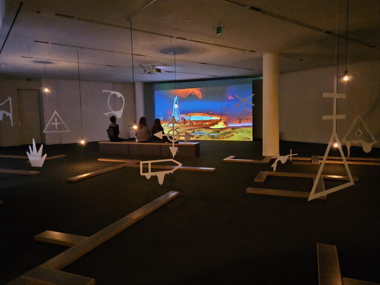 Visitors to the exhibition “Plot Blop Plop” watch the video work “Al-Mather Plot 1991” on Thursday at Atelier Hermes in Seoul. (Park Yuna/The Korea Herald)