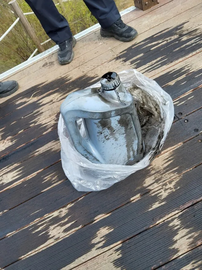 A plastic container stained with black liquid is found on the wooden deck at the summit of Taehaengsan in Hwaseong, Gyeonggi Province, Thursday. (Hwaseong Western Police Station)