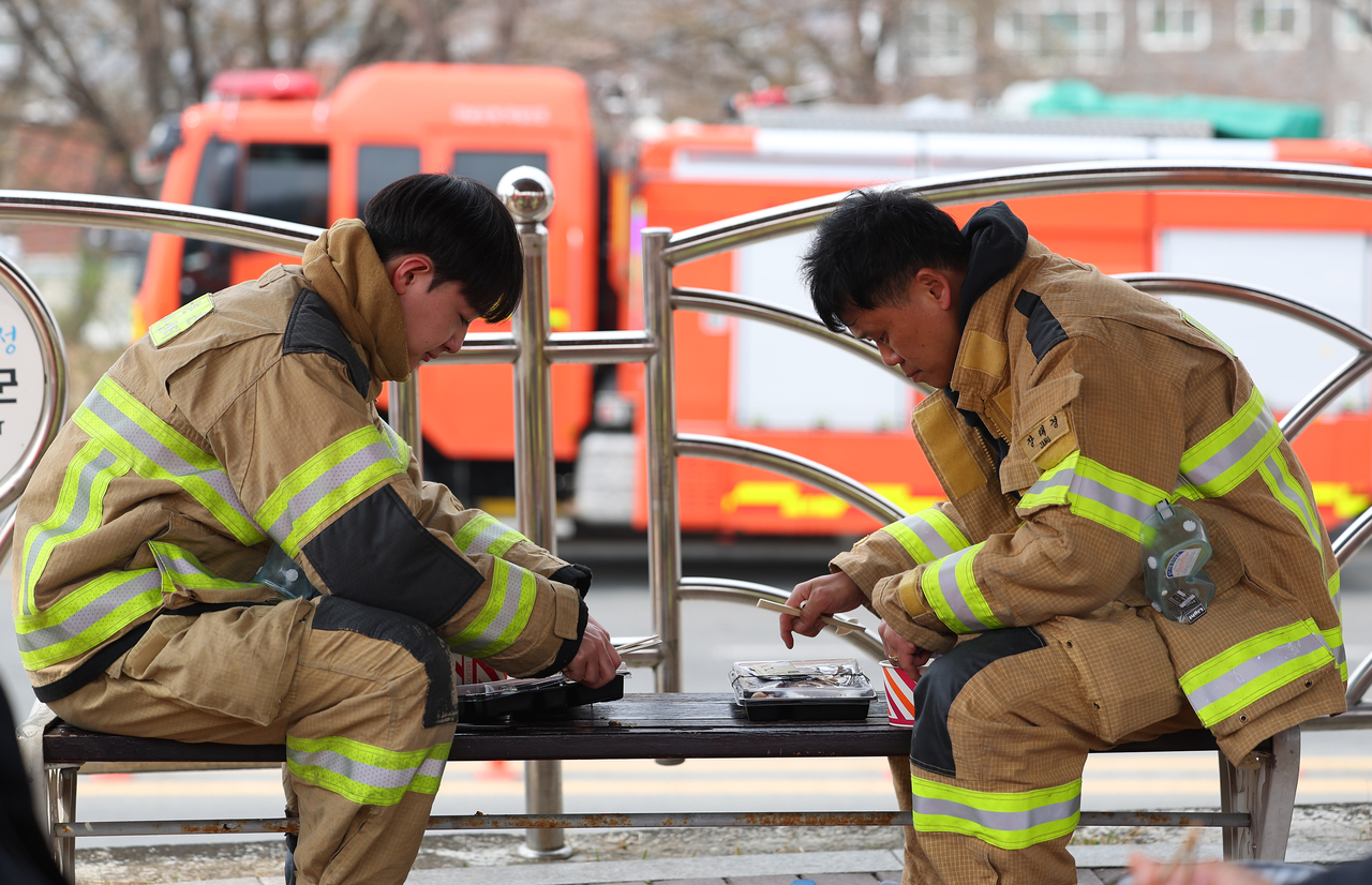 Firefighters dispatched to Uiseong-gun, North Gyeongsang Province, take a break to eat lunch on Friday. (Yonhap)