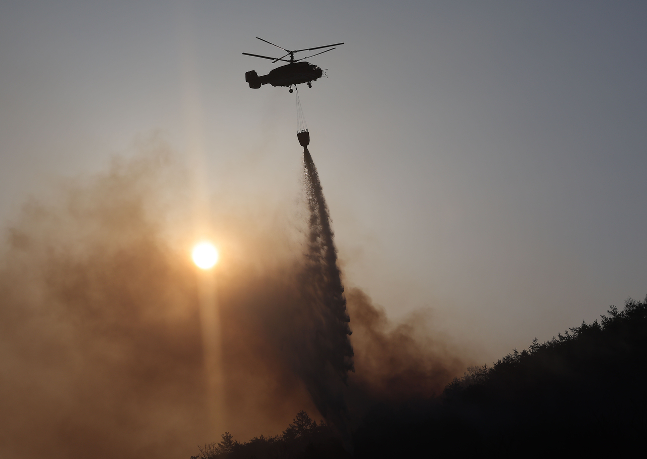 A firefighting helicopter tries to extinguish a wildfire in Andong, North Gyeongsang Province, on Saturday. (Yonhap)