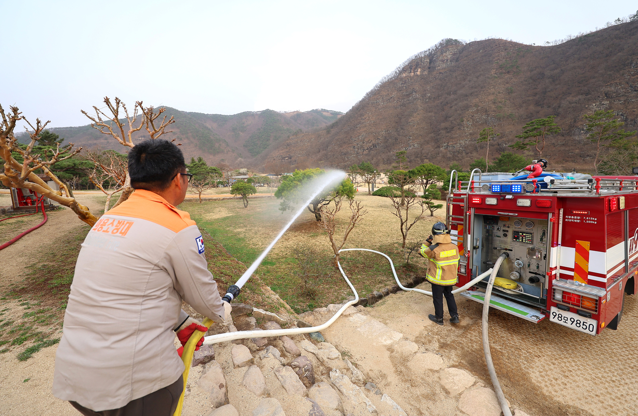 Volunteer firefighters spray water on the Byeongsanseowon compound in Andong, North Gyeongsang Province, in preparation for raging wildfires from nearby Uiseong-gun. (Yonhap)